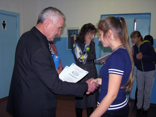 Директор школы награждает грамотой ученика
